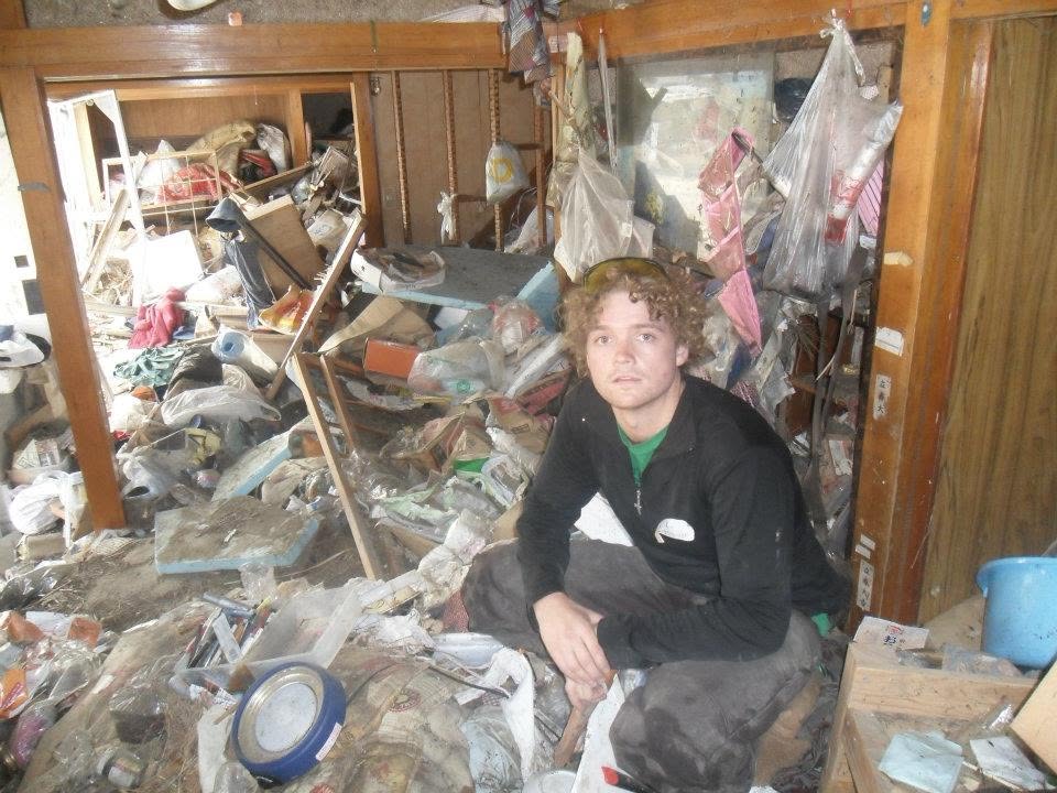 Sam Johnson crouching in a debris-filled house in Japan after the tsunami
