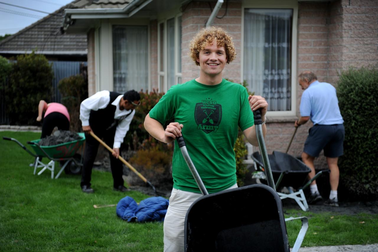 A young Sam Johnson with a wheelbarrow and shovel outside a Christchurch house