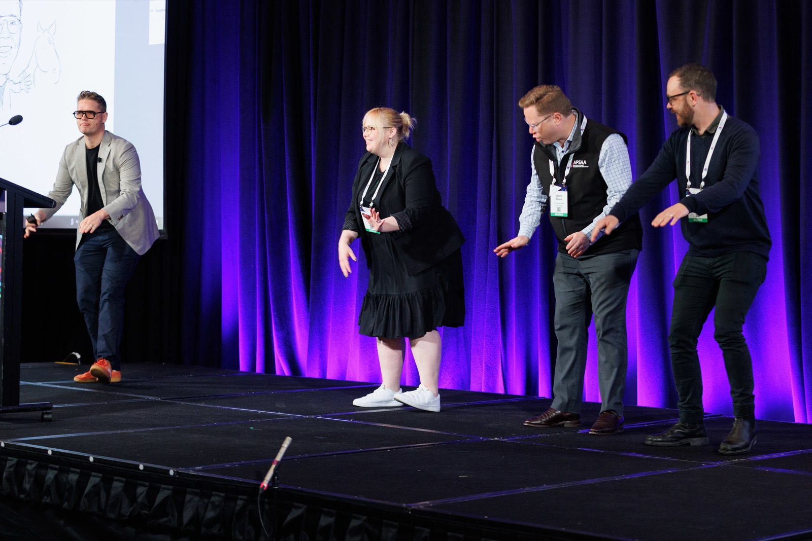 Sam on stage with three people acting out an exercise