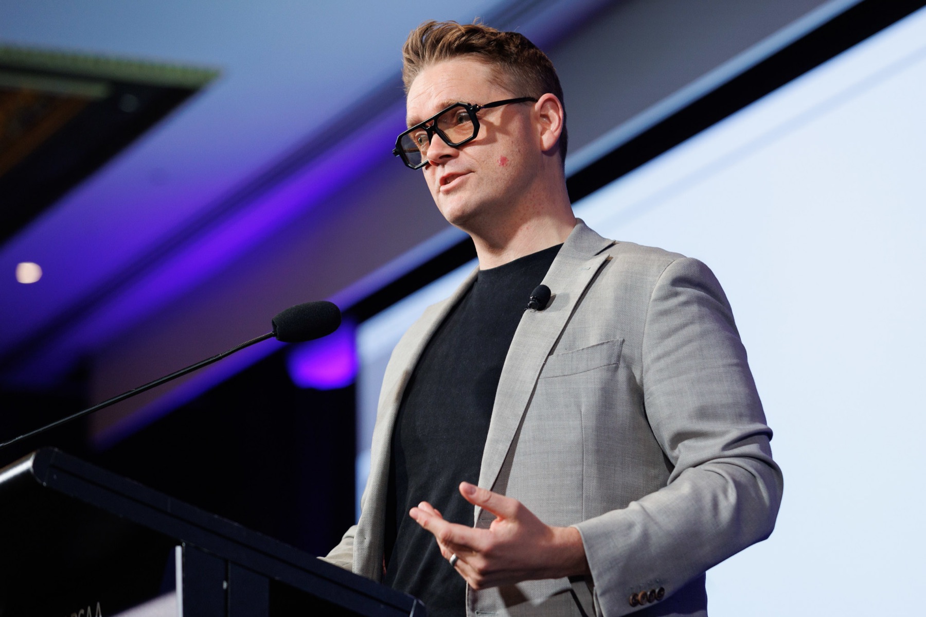 Sam Johnson speaking from a lectern on a conference stage